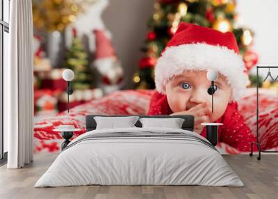 Christmas time. Beautiful little baby boy dressed as Santa celebrates Christmas. Bokeh background. Wall mural