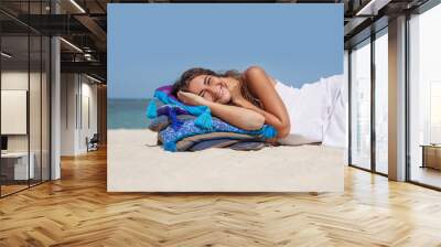 Beautiful woman in white dress lying on pillows at the beach Wall mural