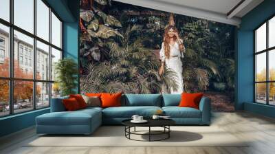 beautiful young cheerful boho style woman at tropical green leaves background Wall mural