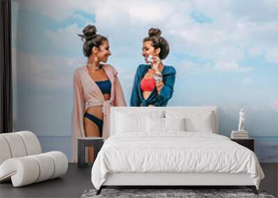 two beautiful stylish young women twin sisters having fun on the beach Wall mural