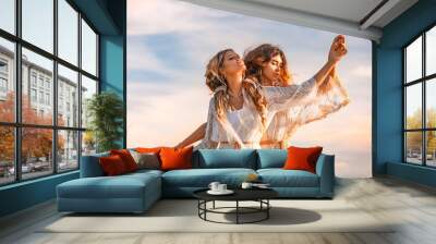 two beautiful young woman in elegant boho dresses oudoors at sunset Wall mural