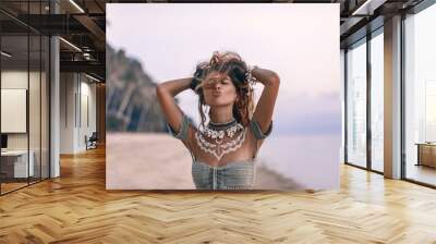 young beautiful boho woman sending air kiss on the beach at sunset Wall mural