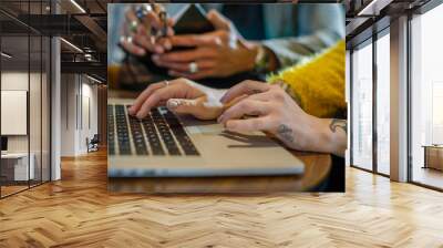 Tattooed woman hands writing and using laptop, man in background.Group of multiethnic people having business team meeting in restaurant lounge.Teamwork,corporate,diversity and social concepts. Wall mural