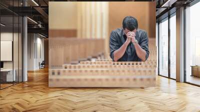 Young beard man wearing blue shirt praying in modern church Wall mural