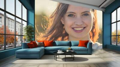 Young smiling brunette hair woman portrait on sunset in nature Wall mural