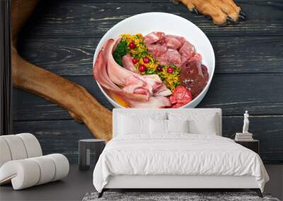 Natural raw organic dog food in bowl on black wooden floor and dog's paws on background Wall mural