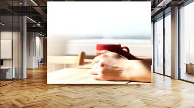 red mug in hands on the background of a window with a copy space. all you need for a warm morning Wall mural