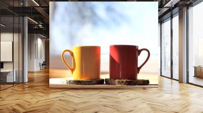 sunny atmosphere of spring morning/ two mugs of a hot drink on table in the background of window with silhouette of tree and blue sky Wall mural