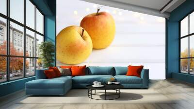 two yellow-orange apples on the table against the background of festive lights. ripe autumn fruits Wall mural