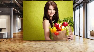 Portrait of a girl holding in hands full of different fruits and Wall mural