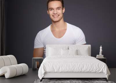 Pretty young man on grey background. Studio shot Wall mural