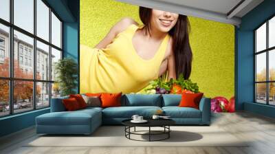 Young smiling woman with fruits and vegetables. Over green backg Wall mural