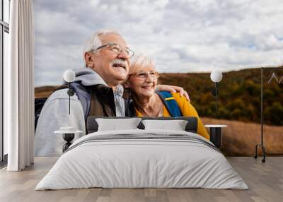 Active senior couple with backpacks hiking together in nature on autumn day. Wall mural