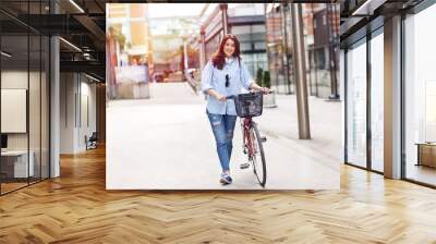 Beautiful young woman with bicycle in urban environment. Wall mural