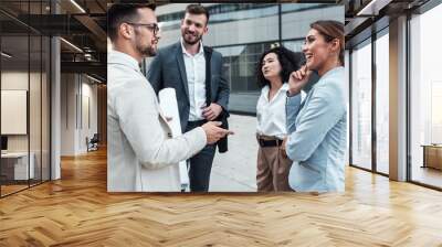 Coworkers standing outside in front of office buildings discuss about business plan. Wall mural