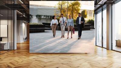 Group of business people walking outside in front of office buildings. Wall mural