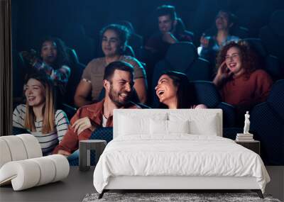 Group of cheerful people laughing while watching movie in cinema. Wall mural