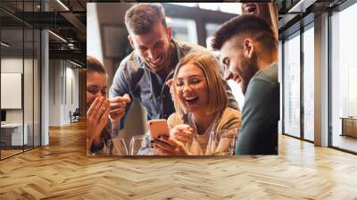 Group of young friends having fun in restaurant talking, laughing while dining at table and making selfie.	 Wall mural