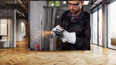 Industrial worker with angle grinder working on metal structure at workshop. Wall mural