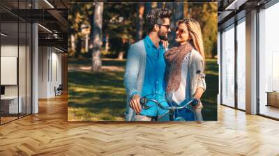 Portrait of happy young couple with a bicycle on sunny day in the park. Wall mural