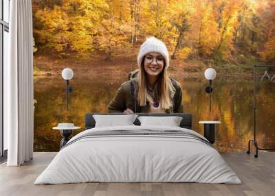 Portrait of young female hiker with backpack standing in forest by the lake. Wall mural