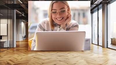 Portrait of young woman using laptop at cafe, she is working on laptop computer at a coffee shop. Wall mural