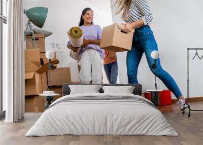 Three female friends carrying boxes into new home. Wall mural