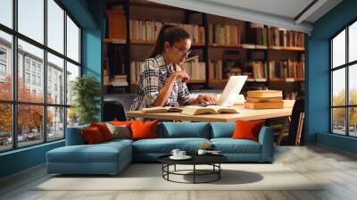 young female student study in the library using laptop for researching online. Wall mural