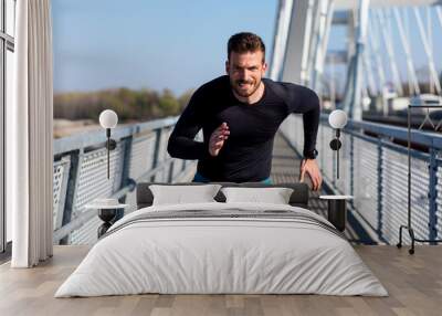 Young male runner sprinting on the bridge in the city during day. Wall mural