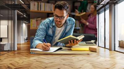 Young male student study in the library reading book. Wall mural