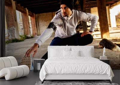 Young man stretching his muscles in old warehouse before running. Wall mural