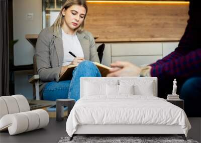 Young man talking to female psychologist during session. Wall mural