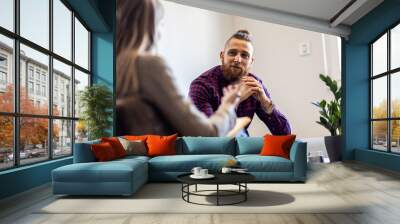 Young man talking to female psychologist during session. Wall mural