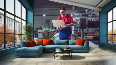 Industrial engineer with laptop in a  industrial manufacture factory working. Wall mural