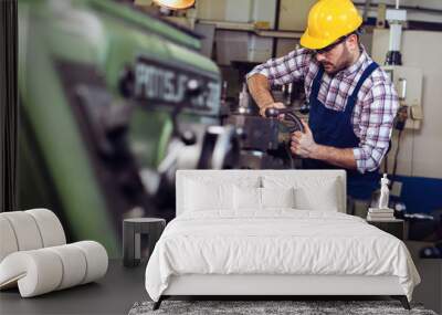 Turner worker is working on a lathe machine in a factory Wall mural