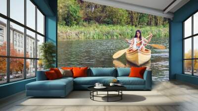 Two women paddling a canoe in a serene nature setting. Wall mural