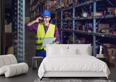 Warehouse worker talking on the phone holding clipboard  Wall mural