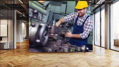 Worker in uniform operating in manual lathe in metal industry factory. Wall mural