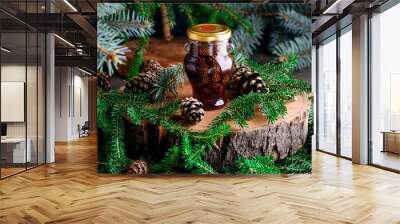 Jam from young pine cones in syrup on a background with pine branches Wall mural