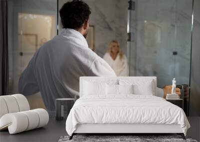 a man enters the bathroom in a dressing gown to a woman. honeymoon at the hotel. white bathrobes Wall mural