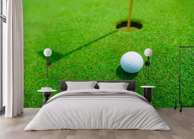 golf ball in the green grass close to the hole with the shadow of the flagpole Wall mural