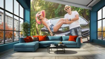 Fashionable young couple ready for driving their convertible car in nature. Wall mural