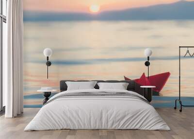 Red paper boat sailing on water at sunset. Travel and vacation concepts.  Wall mural