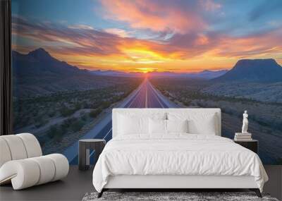 A highway stretching through an expansive desert landscape, with distant mountains and a vibrant sunset, captured to highlight the beauty of nature alongside the open road Wall mural