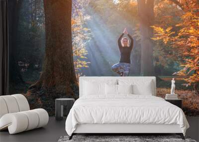 A young woman make yoga position at sunrise. in the autumn forest. Wall mural