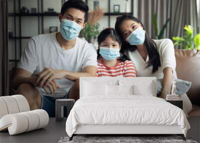 Asian family spending time together at home while wearing face mask. precaution to prevent coronavirus by wearing protective mask. Wall mural