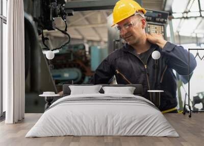 Exhausted factory worker rubs his shoulder due to the back and shoulder aches shows pain expression face, concept working exhaustion, factory worker lifestyle, office syndrome, tiring work hour. Wall mural