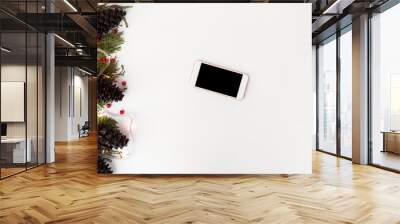 smart phone mobile display on table with isolated white screen for mockup in Christmas time. Christmas tree, gifts, decorations in background. Wall mural