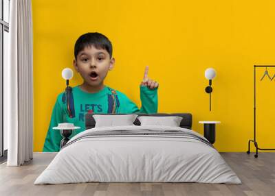 Wow look, advertise here! Portrait of amazed cute little boy pointing to empty place on background, surprised schoolboy showing copy space Wall mural