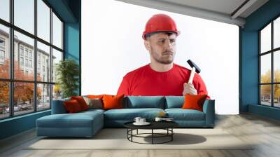 A man in a helmet and a red T-shirt holds a hammer in his hands. Wall mural